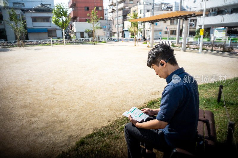 Men reading a book outdoors.